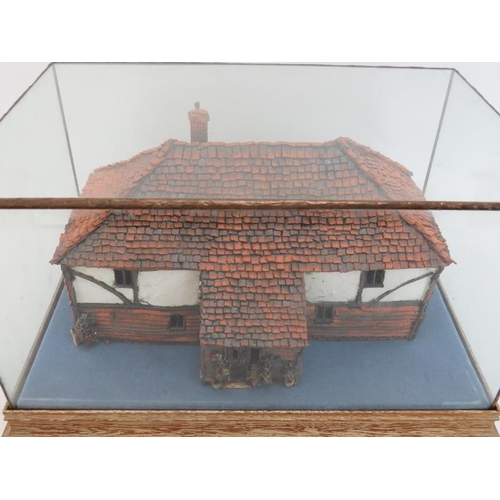 45 - A painted terracotta model of a country cottage, 20th century. Housed within a glass display case. C... 