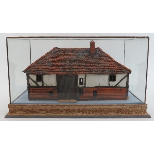 45 - A painted terracotta model of a country cottage, 20th century. Housed within a glass display case. C... 