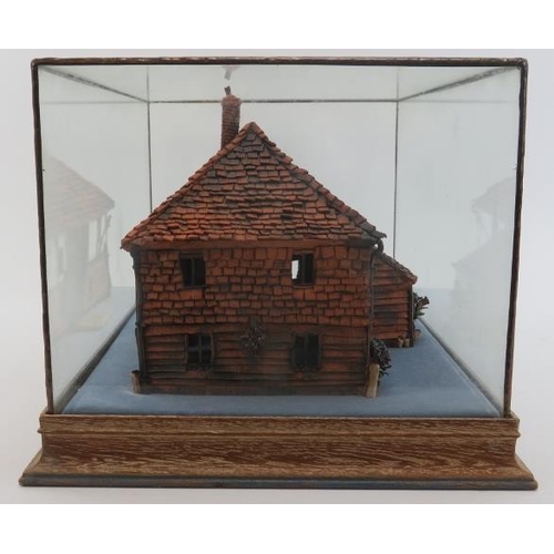 45 - A painted terracotta model of a country cottage, 20th century. Housed within a glass display case. C... 