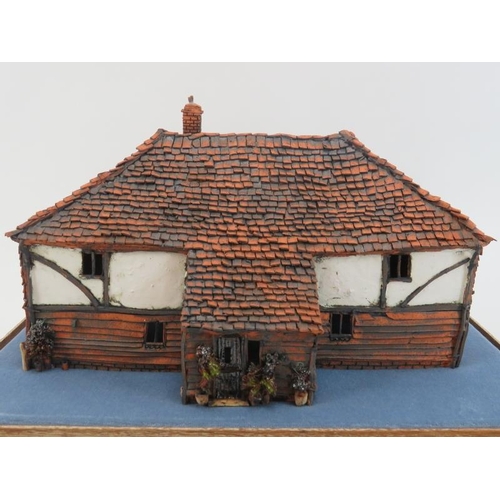 45 - A painted terracotta model of a country cottage, 20th century. Housed within a glass display case. C... 