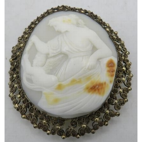 451 - A large vintage cameo brooch in a filigree frame depicting a classical maiden tempting a cherub with... 