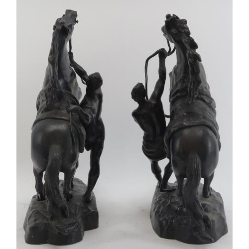 64 - A pair of bronzed metal male figures with rearing marly horses. Modelled after works by the French s... 