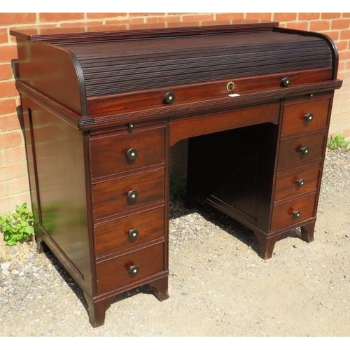 703 - An Edwardian mahogany roll-top desk, the tambour door opening onto a fitted interior, above an array... 