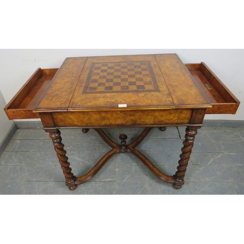 730 - A reproduction burr walnut games table by Theodore Alexander, the sliding central section with inlai... 