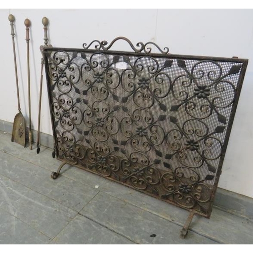 788 - A wrought iron and mesh freestanding fire screen with scrolled and applied rosette detail, on scroll... 