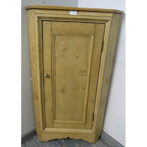 795 - An antique stripped pine floor standing corner cupboard, the panelled door opening onto one fitted s... 