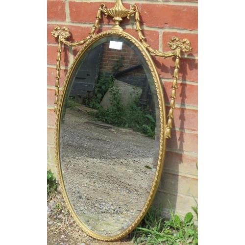 825 - A vintage oval bevelled wall mirror in the Neo-Classical taste, the gilt surround with urn finial fl... 