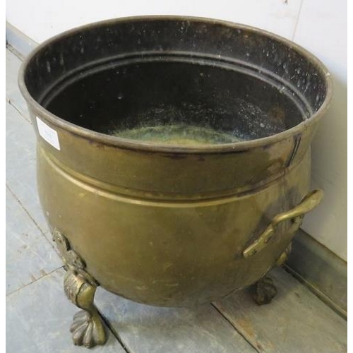 830 - A vintage brass log bin on cast brass supports with acanthus moulding, terminating on hairy paw feet... 