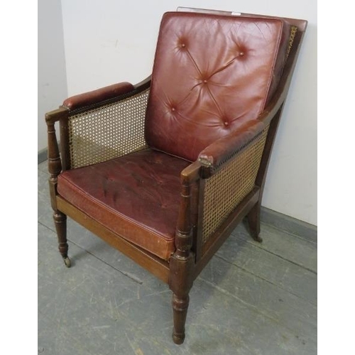 842 - An Regency Period bergère library chair, with loose cushions upholstered in oxblood buttoned leather... 