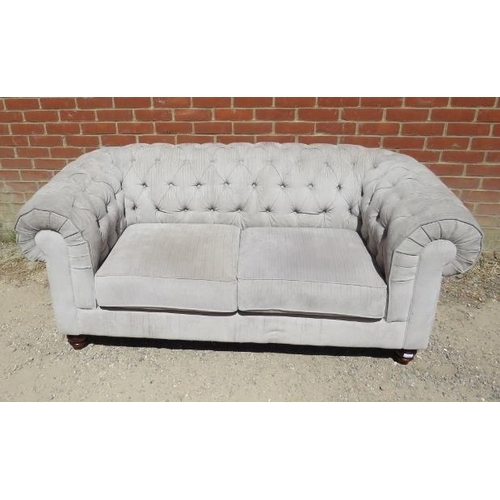 864 - A contemporary two-seater Chesterfield sofa, upholstered in buttoned grey material, on tapering mang... 