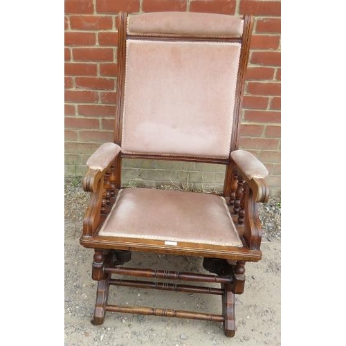 869 - An Edwardian walnut ‘Dexter’ rocking chair, with turned spindles, upholstered in beige velvet materi... 