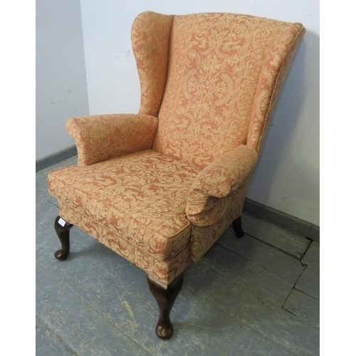 872 - A Parker Knoll wingback armchair upholstered in terracotta patterned material, with sprung seat and ... 