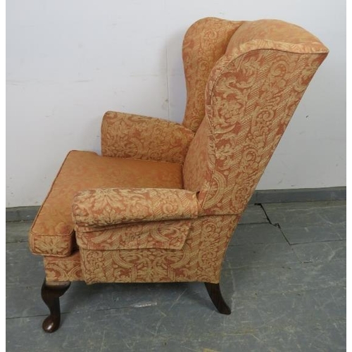 872 - A Parker Knoll wingback armchair upholstered in terracotta patterned material, with sprung seat and ... 