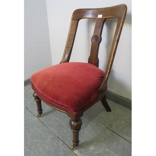 890 - An Arts & Crafts oak bedroom chair with rosette carved backsplat, upholstered in claret velvet, on t... 