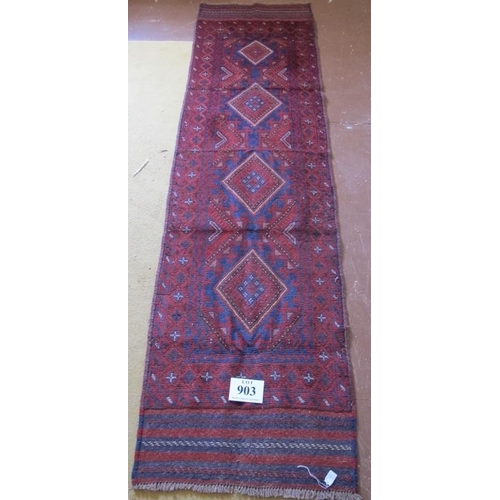 903 - A Meshwani runner, five central diamond motif on deep red ground. 251cm x 65cm.