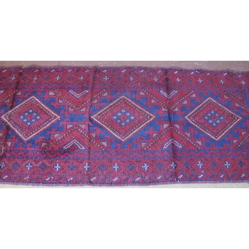 903 - A Meshwani runner, five central diamond motif on deep red ground. 251cm x 65cm.