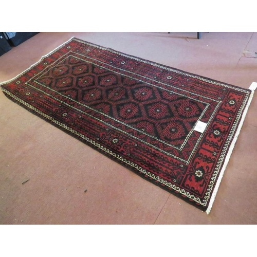 919 - A North East Persian meshed Belouch rug deep burgundy high lighted with black and white. In good con... 