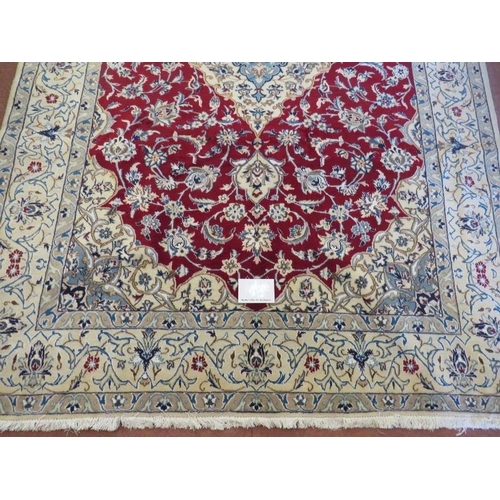 921 - A Persian meshed rug, central cream floral motif on a red ground and cream borders. 255cm x 165cm.