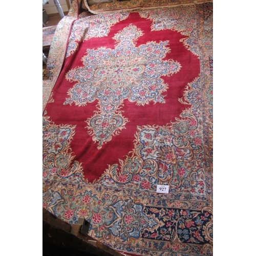 927 - A mid 20th century Persian carpet with a large central floral motif on a red ground with deep 52cm b... 