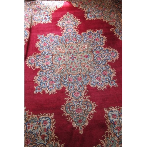 927 - A mid 20th century Persian carpet with a large central floral motif on a red ground with deep 52cm b... 