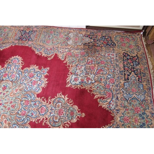 927 - A mid 20th century Persian carpet with a large central floral motif on a red ground with deep 52cm b... 