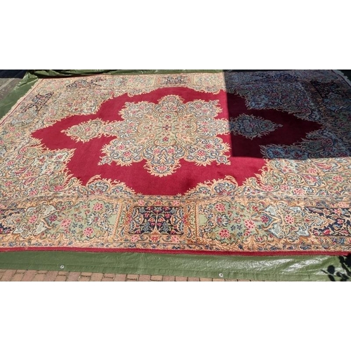 927 - A mid 20th century Persian carpet with a large central floral motif on a red ground with deep 52cm b... 