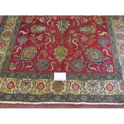 931 - A North West Persian Tabriz rug, a central area depicting flowers on red ground, surrounded by a tri... 