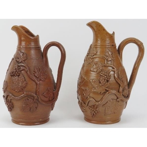 23 - A matched pair of Victorian stoneware wine jugs. With vine leaf and berry relief moulded decoration.... 