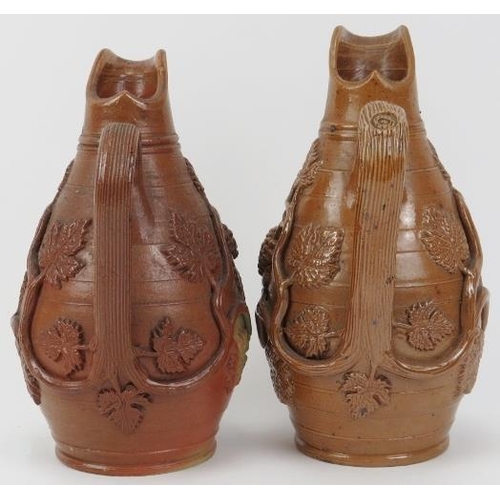 23 - A matched pair of Victorian stoneware wine jugs. With vine leaf and berry relief moulded decoration.... 