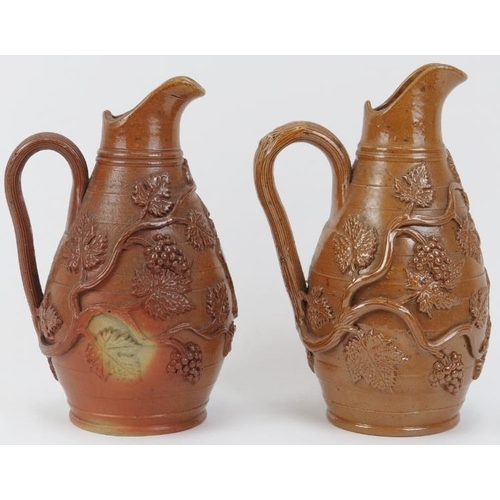 23 - A matched pair of Victorian stoneware wine jugs. With vine leaf and berry relief moulded decoration.... 