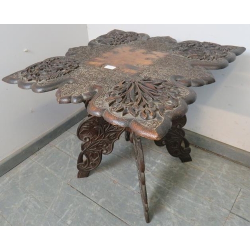 703 - A well carved antique Anglo-Indian hardwood folding table, the shaped top with relief carving depict... 