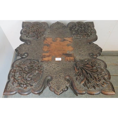 703 - A well carved antique Anglo-Indian hardwood folding table, the shaped top with relief carving depict... 