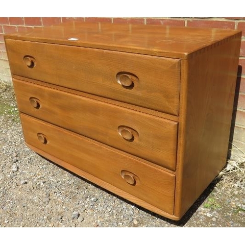 711 - A mid-century blonde elm Windsor chest by Ercol (model 412) housing three long drawers, raised on ca... 