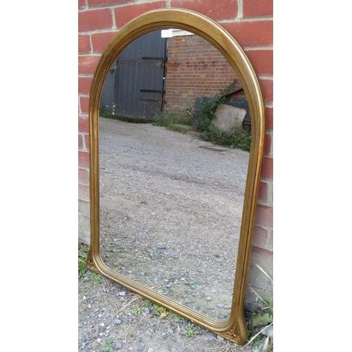 722 - A reproduction arched overmantel mirror in a giltwood frame with carved foliate detail to corners. 
... 