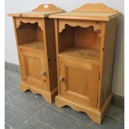 739 - A pair of pine bedside cabinets with shaped galleries, above an open shelf with cupboard under, on p... 