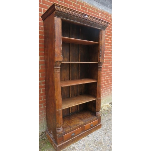 748 - A very large open bookcase of reclaimed antique tropical hardwood, featuring carved frieze and pilas... 