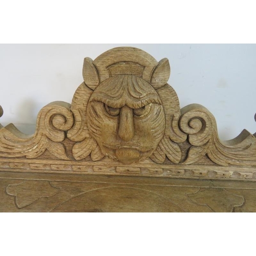 791 - An Arts & Crafts Period limed oak stick stand, the carved rear gallery with grotesque mask amidst sc... 