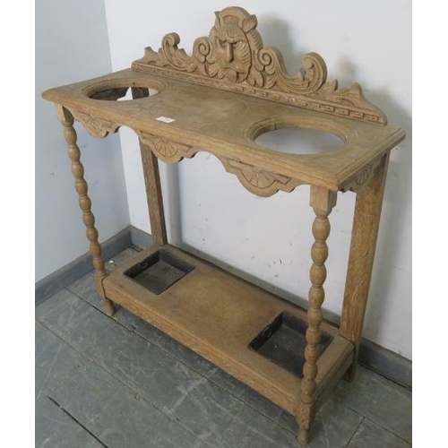 791 - An Arts & Crafts Period limed oak stick stand, the carved rear gallery with grotesque mask amidst sc... 