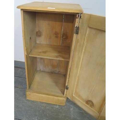 796 - An antique stripped pine bedside cabinet, the panelled door opening onto one loose shelf, on a plint... 