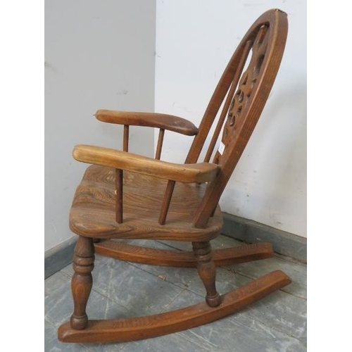 815 - A vintage ash child’s rocking chair with carved and pierced back splat, on turned supports with rock... 