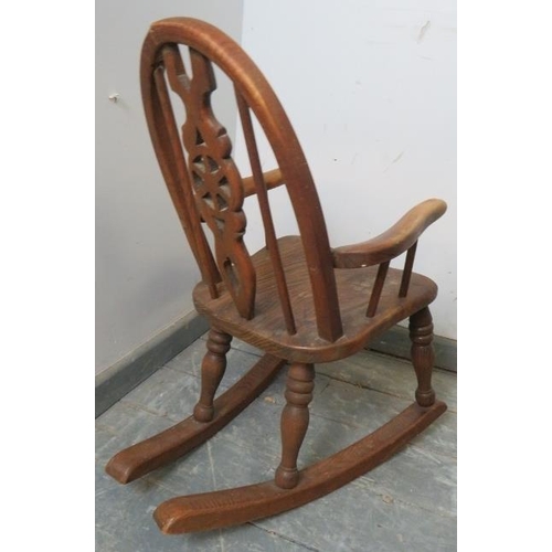 815 - A vintage ash child’s rocking chair with carved and pierced back splat, on turned supports with rock... 