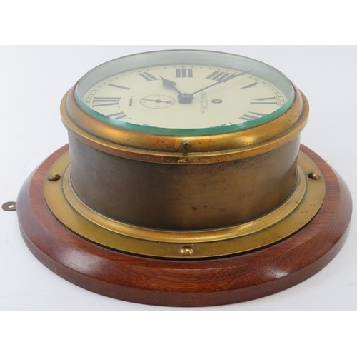 105 - A ships bulkhead wall clock, early/mid 20th century. With a brass case, enamelled dial and mounted o... 