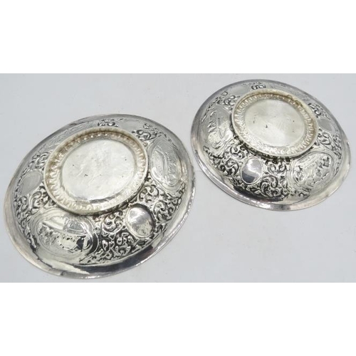 303 - A pair of white Anglo Indian metal dishes heavily embossed with foliate design and cartouche of vill... 