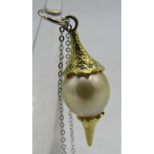 358 - A bespoke Australian Golden Southsea pearl pendant set between planished yellow metal mounts. The to... 