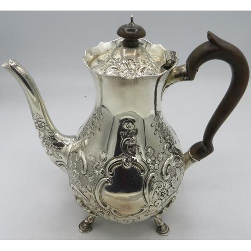 416 - A fine heavily embossed silver coffee pot decorated with scrolls and flowers on hoof feet with woode... 