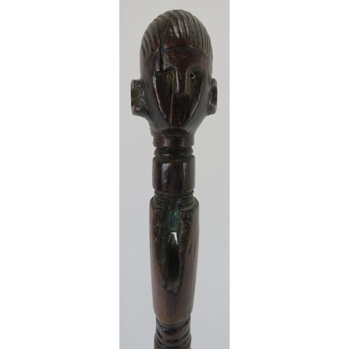 58 - Tribal Art: An African carved hardwood axe handle. One end terminating with a carved head. Displayed... 