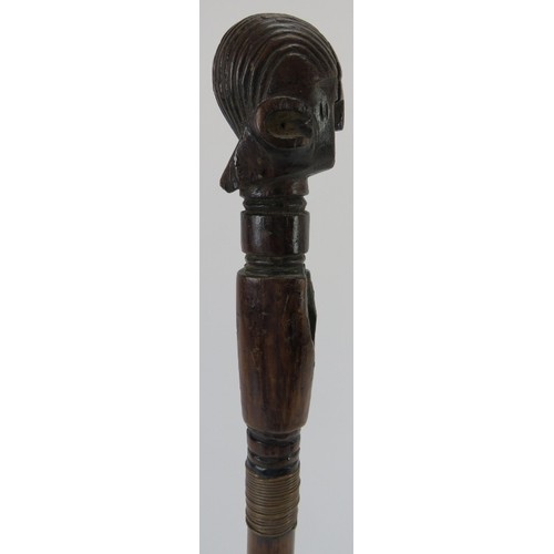 58 - Tribal Art: An African carved hardwood axe handle. One end terminating with a carved head. Displayed... 