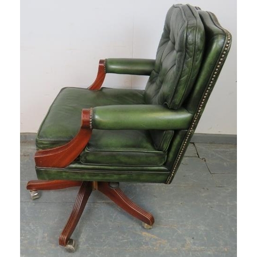 705 - An antique style mahogany swivel desk chair, with height adjust, upholstered in green buttoned leath... 