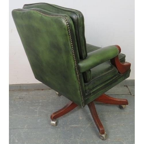 705 - An antique style mahogany swivel desk chair, with height adjust, upholstered in green buttoned leath... 