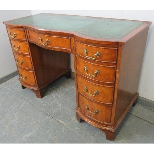 745 - An antique style walnut serpentine front kneehole desk with inset green leather writing surface, hou... 